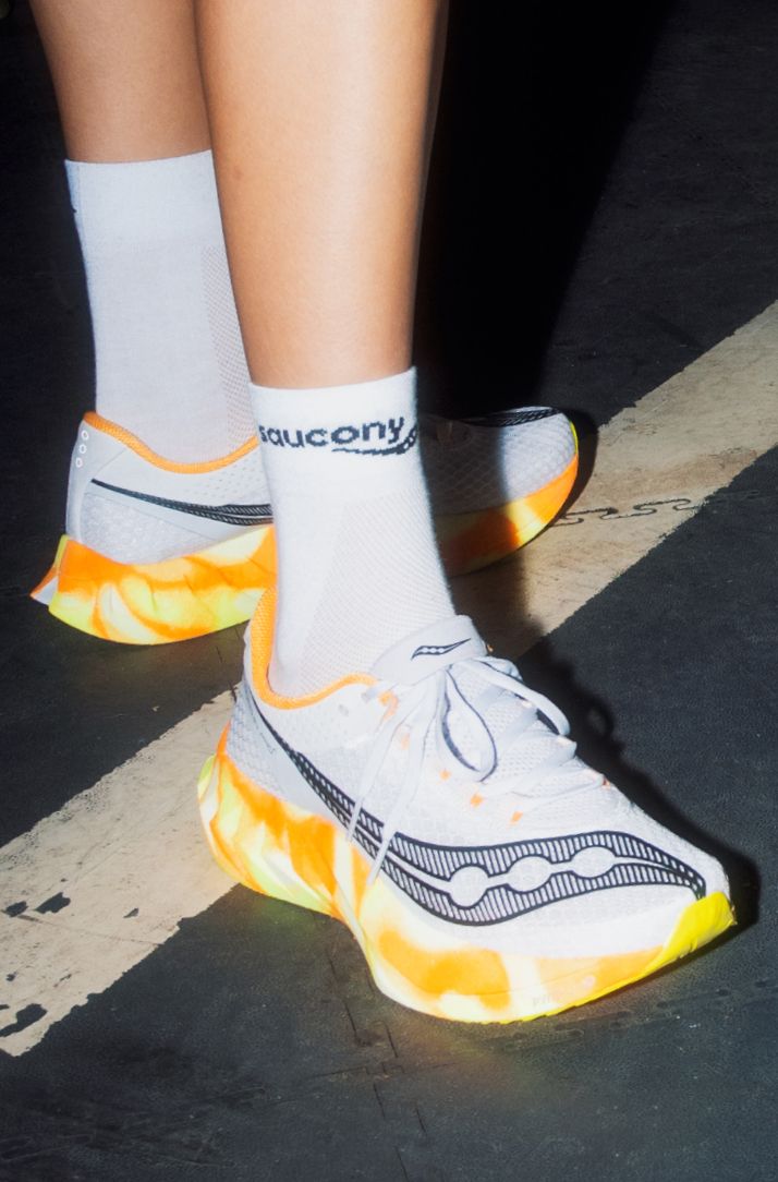 a person's feet in white and orange shoes
